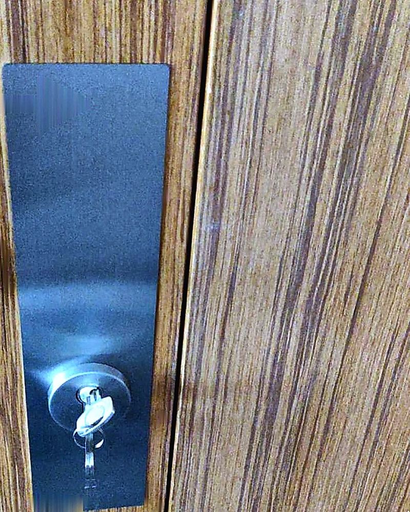 Stainless steel cover plate and new cylinder lock on a wooden door, hiding the holes from the old lock