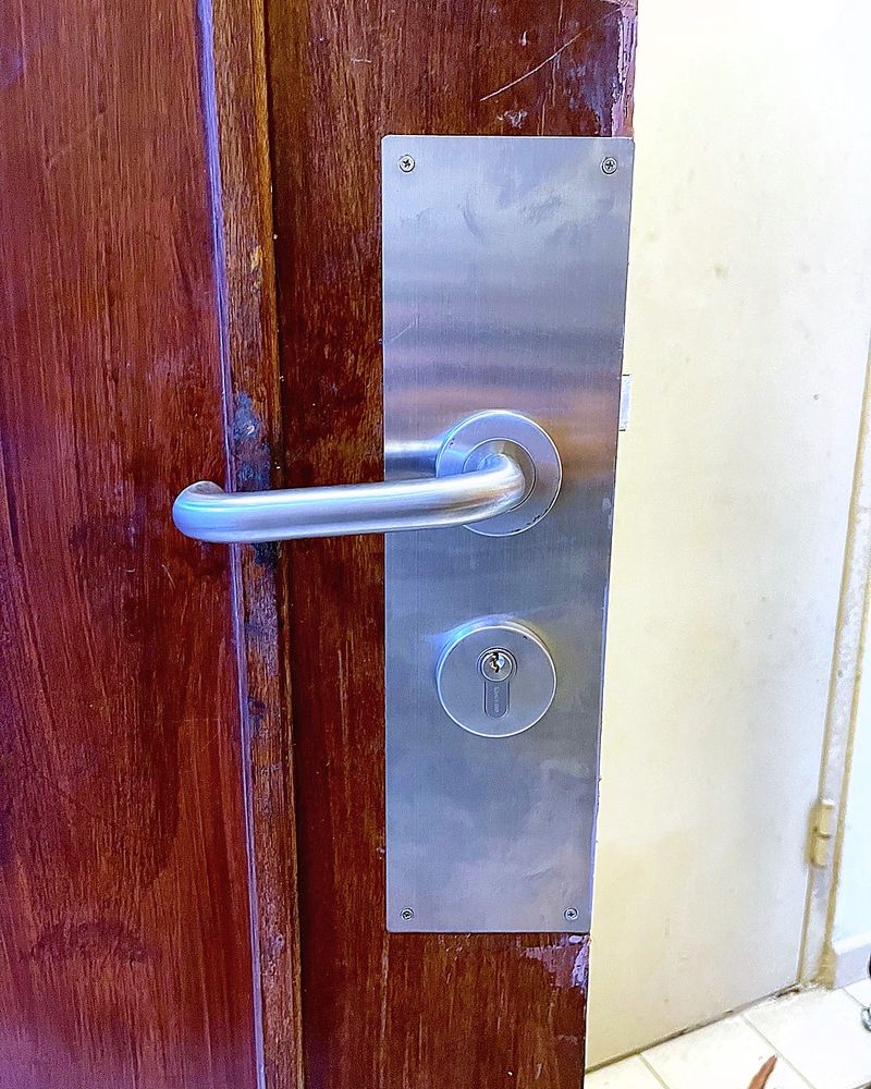 New stainless steel lever handle and lock plate fitted on a wooden main door in Singapore