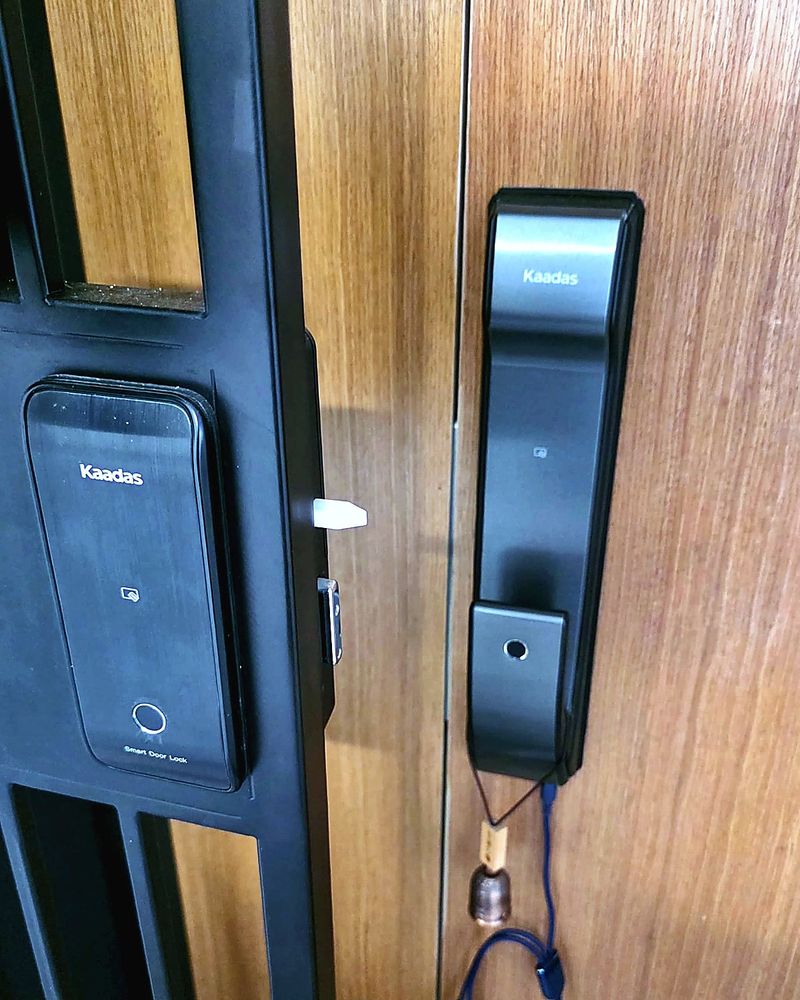 Kaadas digital locks on a black metal gate and a wooden main door in Singapore