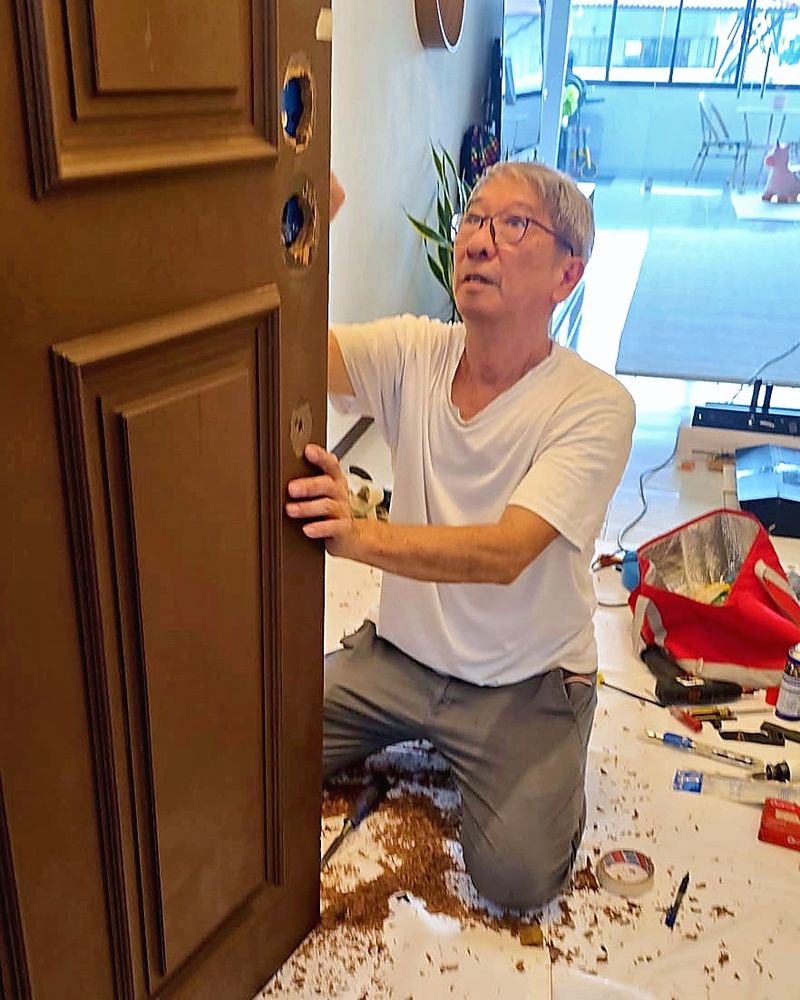 Locksmith from Uncle Thomas's team fitting a new lock to a main door, with the floor covered to protect the home